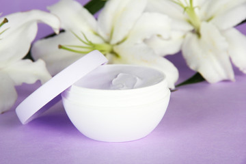Obraz na płótnie Canvas Cosmetic cream i piękna lilia, na fioletowym tle