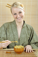 Junge Frau in Kimono isst Reisgericht mit Stäbchen
