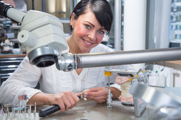 Zahntechnikerin in einem Dentallabor mit Zahnersatz.