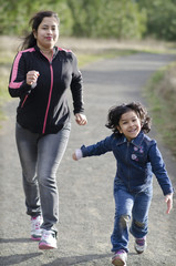 Mom and daughter running in a park