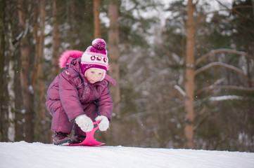 Fototapeta na wymiar Adorable girl sled from hill in park