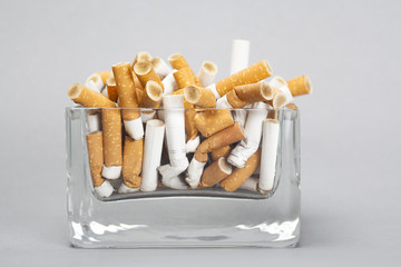 Ashtray full of cigarettes on gray background