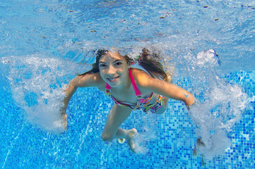 Underwater child in swimming pool, girl swims and having fun