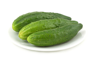 Three green cucumbers on plate isolated on white closeup