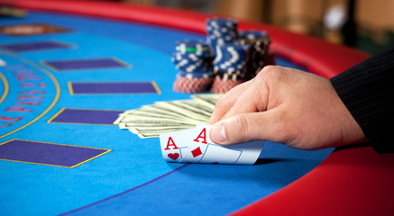 men's hand with chips, cards and dollars banknotes on table