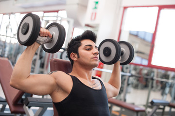 Fototapeta na wymiar Młody mężczyzna ćwiczeń z hantlami w siłowni.