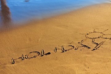 Holiday text written in sand
