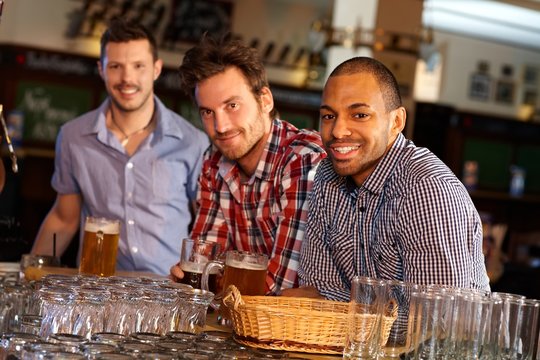Young men drinking beer at bar counter