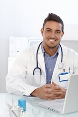 Happy doctor sitting at desk