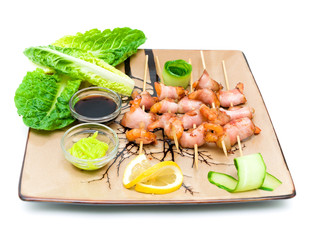 Shrimp with bacon on plate on white background