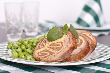Table setting. Meatloaf, garnished with green peas, mint sprig