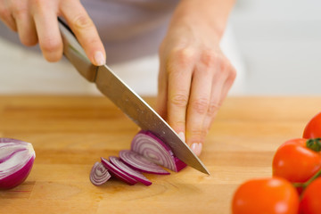 Closeup on woman cutting red onion