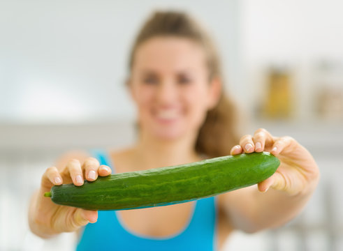 Closeup on cucumber in hand of young woman