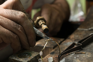 Jeweler melting gold bracelet with gasoline burner