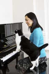 Mature woman and her cat playing piano