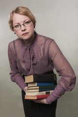 The young woman holds a pile of books