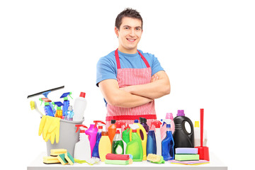 Young man in apron posing with cleaning supplies