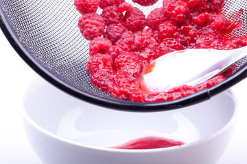 sieving raspberries for jam