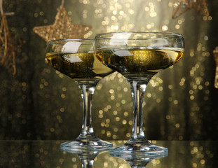 Two glasses of champagne on bright background with lights