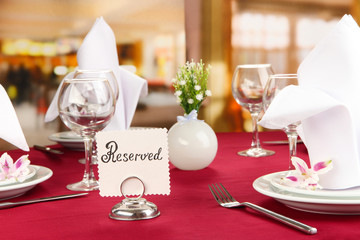 Reserved sign on restaurant table with empty dishes and glasses