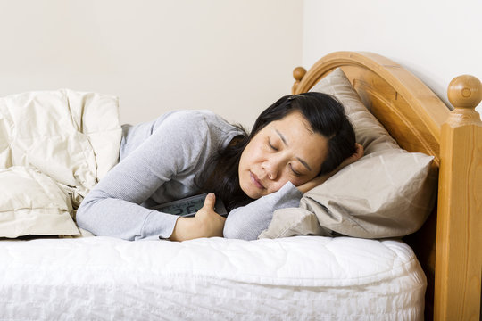 Mature woman falling alseep with alarm clock
