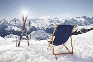 Cross ski and Empty sun-lounger at mountains in winter - obrazy, fototapety, plakaty