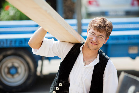 zimmermann tr&auml;gt holzbalken auf der schulter