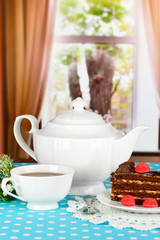 Teapot, cup of tea and delicious cake on window background