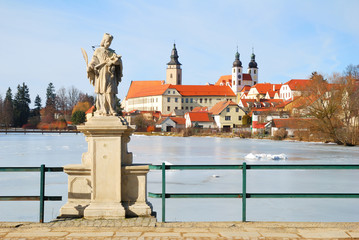 Telc chateau and church above a frozen pond and statue of saint