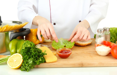 Female hands preparing cheeseburger, isolated on white