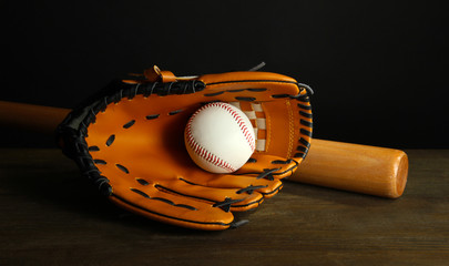 Baseball glove, bat and ball on dark background