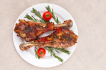 Roasted turkey legs on white plate with cherry tomato and rosema