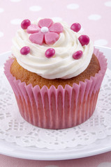 Cupcake mit rosa Blume und roten Schokolinsen