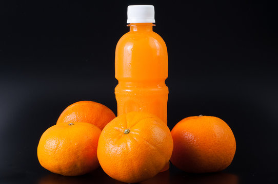 Orange Juice In A Bottle And Orange On Black Background