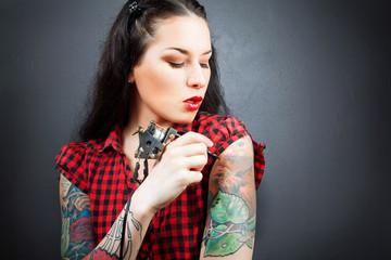 Photo of beautiful girl with tattoos and tattoo machine.