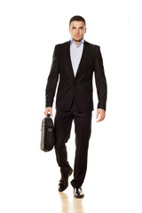 attractive young businessman walking with a laptop bag