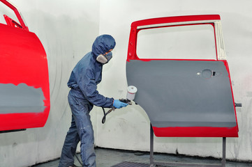 Worker painting car door.
