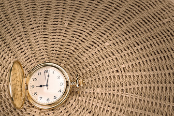 Antique pocket watch on a textured woven straw. Close-up.