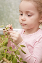 portrait of little girl doing plant's leafs cleaning