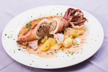 Squid being served with scoops of chicken and potatoes.