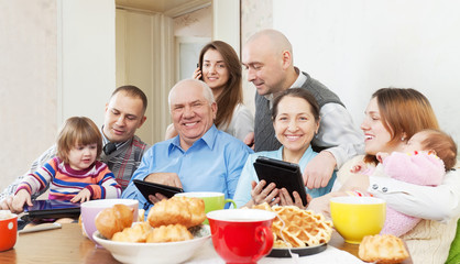 Obraz na płótnie Canvas szczęśliwa rodzina wielopokoleniowych korzysta z urządzeń elektronicznych