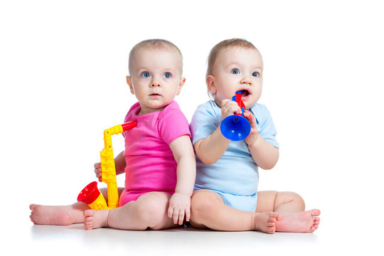 Funny babies girl and boy  playing musical toys. Isolated on whi