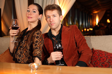 man and woman with a glass of wine watching the camera
