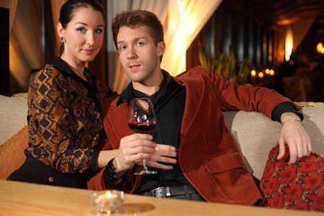 man with a glass of wine and a woman looking at the camera