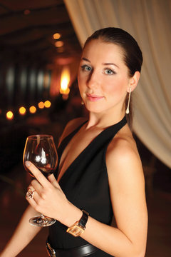 beautiful woman in a black dress with a glass of wine on a dark