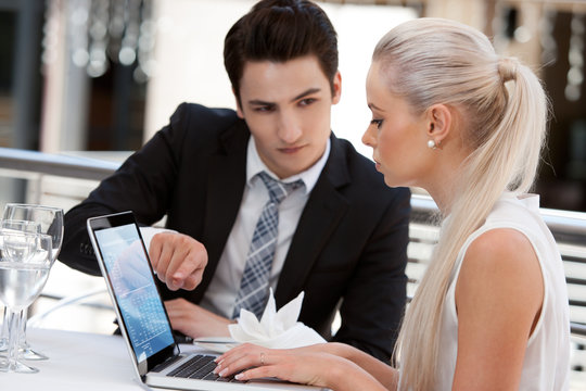 Business partners working on laptop at restaurant.