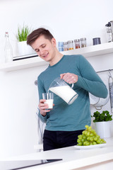 young man drinking a glass of milk in the kitchen