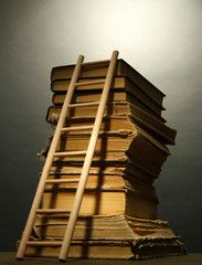 Old books and wooden ladder, on grey background