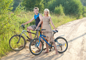 Fototapeta na wymiar The guy and the girl by bicycles on the rural road