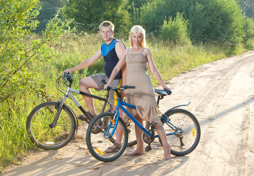 The guy and the girl by bicycles on the rural road